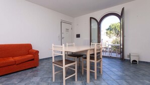 A room with a dining table, chairs, a sofa, and a door leading to a balcony. - M290 - Marcelli, new three-room apartment with terrace (Marcelli)
