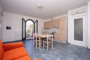 A modern kitchen with wooden cabinets, a dining table with chairs, and a large window.