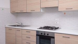 A kitchen with light wood cabinets, a white countertop, a gas stove, and an oven. - M290 - Marcelli, new three-room apartment with terrace (Marcelli)