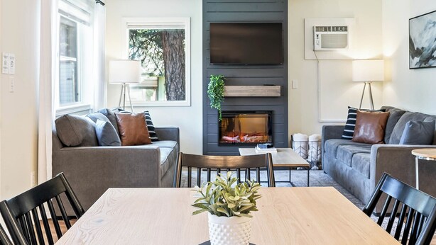 Una sala de estar moderna con chimenea, una mesa de comedor con sillas y una araña.