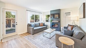 Una sala de estar moderna con un sofá gris, una mesa de centro y una chimenea.