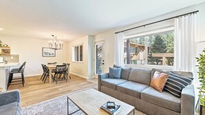 Una sala de estar moderna con un sofá gris, una mesa de centro y una zona de comedor con una mesa y sillas.