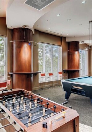 Relax and unwind in this spacious recreational room, featuring a foosball table, pool table, and comfortable seating area.