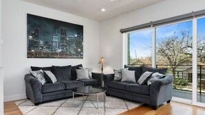 A living room with two grey sofas, a round coffee table, and a cityscape painting on the wall. - Midtown with a View! (Houston)