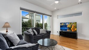 A modern living room with a grey sofa set, a black coffee table, and a flat-screen TV on a black stand. - Midtown with a View! (Houston)