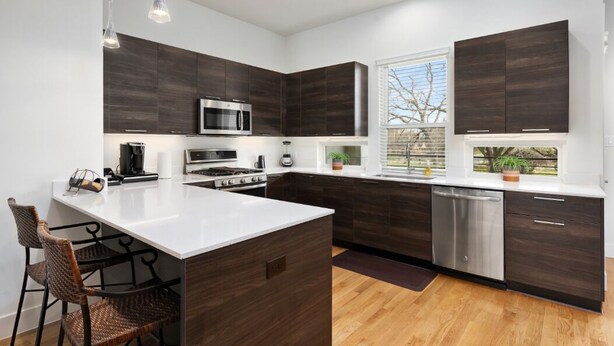 A modern kitchen with dark wood cabinets, stainless steel appliances, and a central island with seating. - Midtown with a View! (Houston)