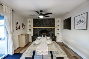 Een eetkamer met een stenen open haard, een plafondventilator en een lijstwerk met kunst.