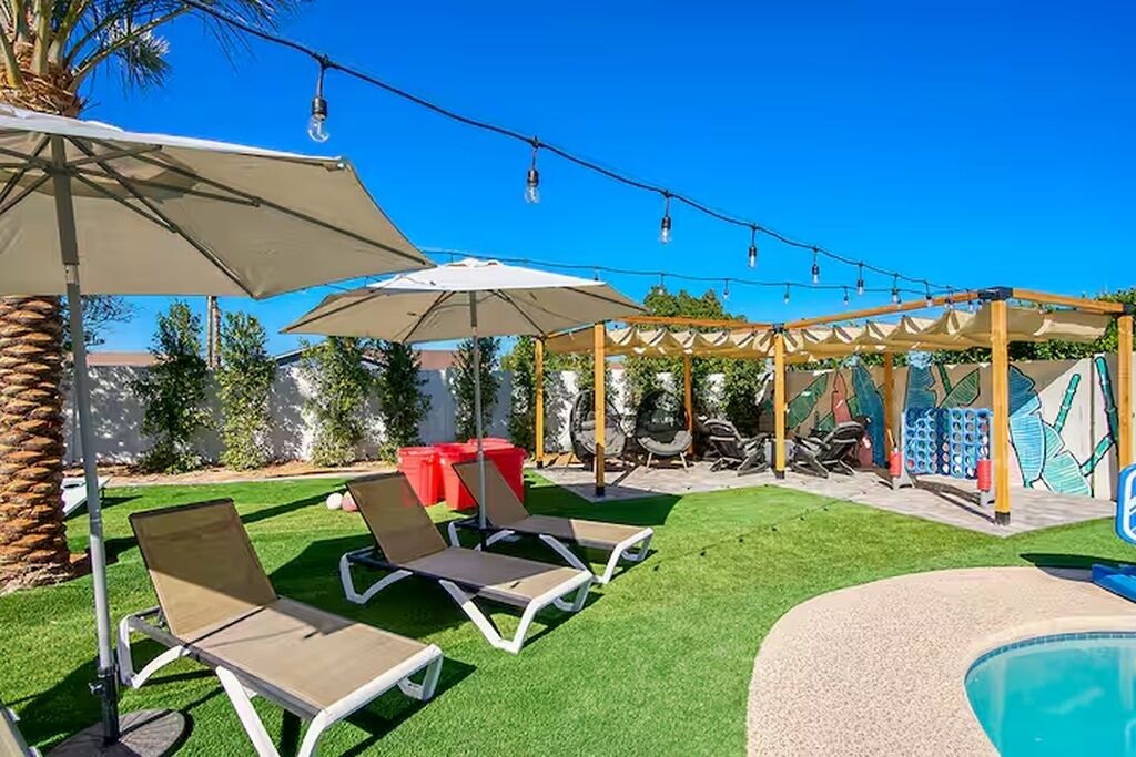 A poolside area with lounge chairs, umbrellas, and string lights.