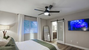 A bedroom with a bed, a ceiling fan, a TV, and a window with curtains. - Entertainer’s Retreat: Pool, Hot Tub & Mini Golf! (Mesa)