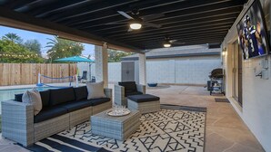 An outdoor patio area with a covered seating area, a pool, and a barbecue grill. - Entertainer’s Retreat: Pool, Hot Tub & Mini Golf! (Mesa)