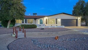 A modern two-story house with a garage, surrounded by landscaped gravel and small trees. - Entertainer’s Retreat: Pool, Hot Tub & Mini Golf! (Mesa)