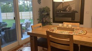 Un comedor con una mesa de madera, sillas, un centro de mesa floral y una lámpara.