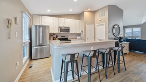 A modern kitchen with white cabinets, stainless steel appliances, and a central island with bar stools.