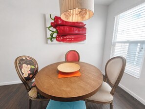 Een eetgedeelte met een ronde houten tafel, twee stoelen en een wandlamp.
