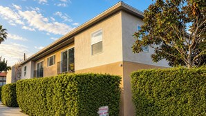 Un edificio residencial de dos pisos con techo plano, ventanas grandes y un cartel de 'No Parking'.