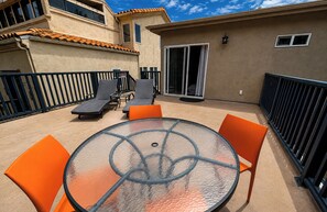 An outdoor patio with a round glass table, orange chairs, and a sun lounger. - LA JOLLA SHORES PAD (LA JOLLA)