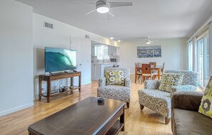 A living room with a TV, wooden coffee table, patterned armchairs, and a dining area with a table and chairs. - Spacious Upper unit located just two houses from the sand! (Newport Beach)