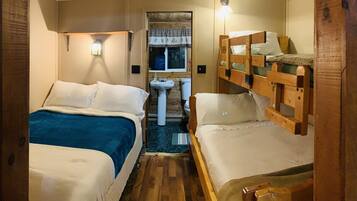 Une petite chambre avec deux lits, un petit lavabo et une fenêtre avec des rideaux.