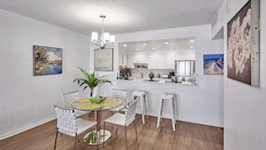 A modern kitchen with white cabinets, a central island, and a dining area with a round table and chairs.
