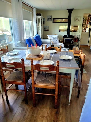 Un coin repas avec une table en bois dressée pour quatre personnes, entourée de chaises en bois.