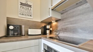 A modern kitchen with a coffee machine, toaster, and a decorative sign on the wall.