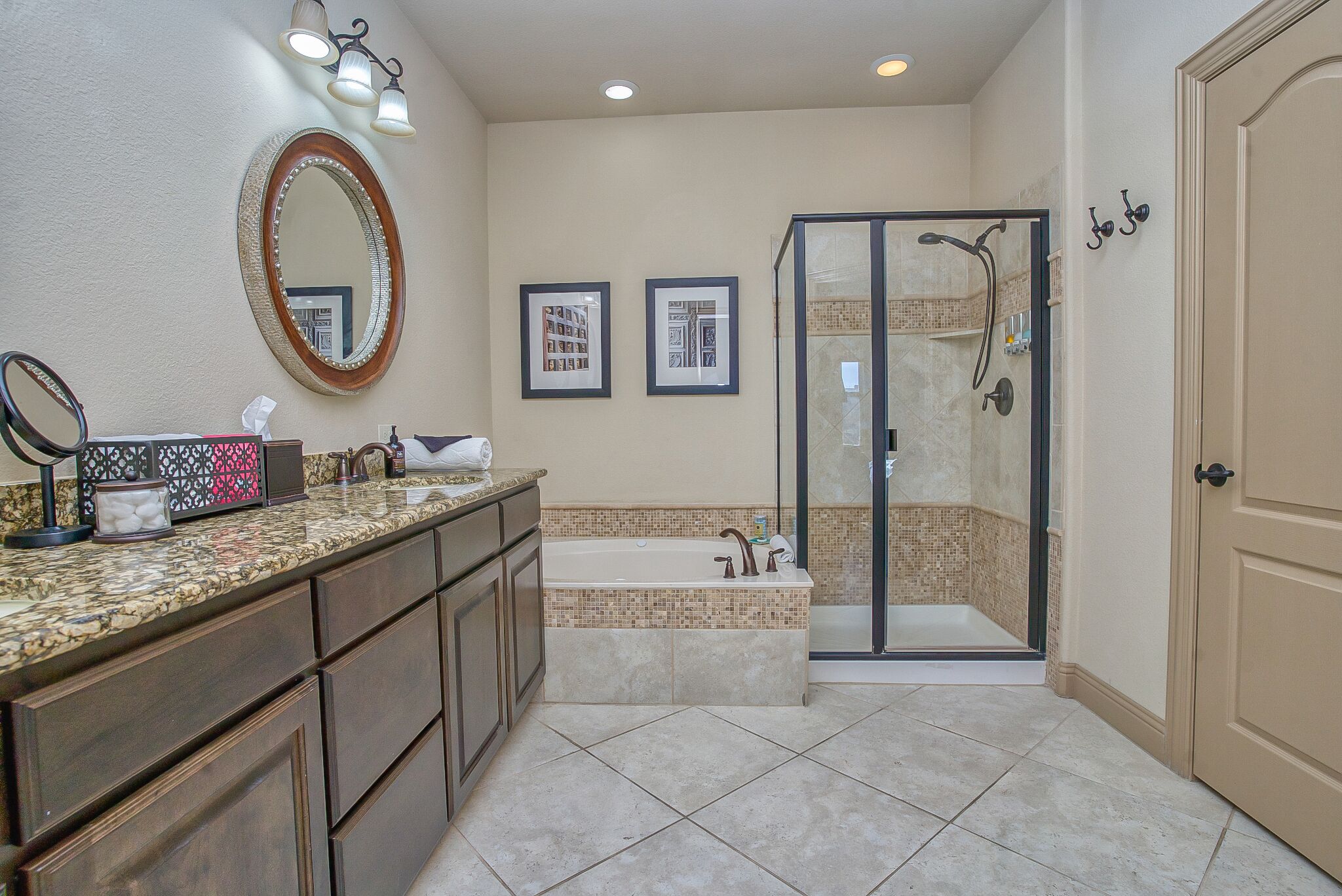 A bathroom with a double vanity, a large mirror, a bathtub, and a walk-in shower.