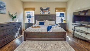 Ein Schlafzimmer mit einem großen Bett, einem Deckenventilator, einem Fernseher und einer Kommode.