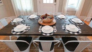 Mesa de comedor para seis personas con manteles individuales de cuadros, platos blancos y vasos.