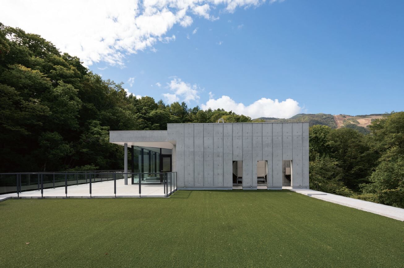 A modern building with a flat roof, large glass windows, and a concrete exterior.