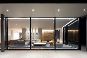A modern interior with a glass partition, a grey sofa set, and a stone accent wall. - YAMAKEI Residences (Kutchan)