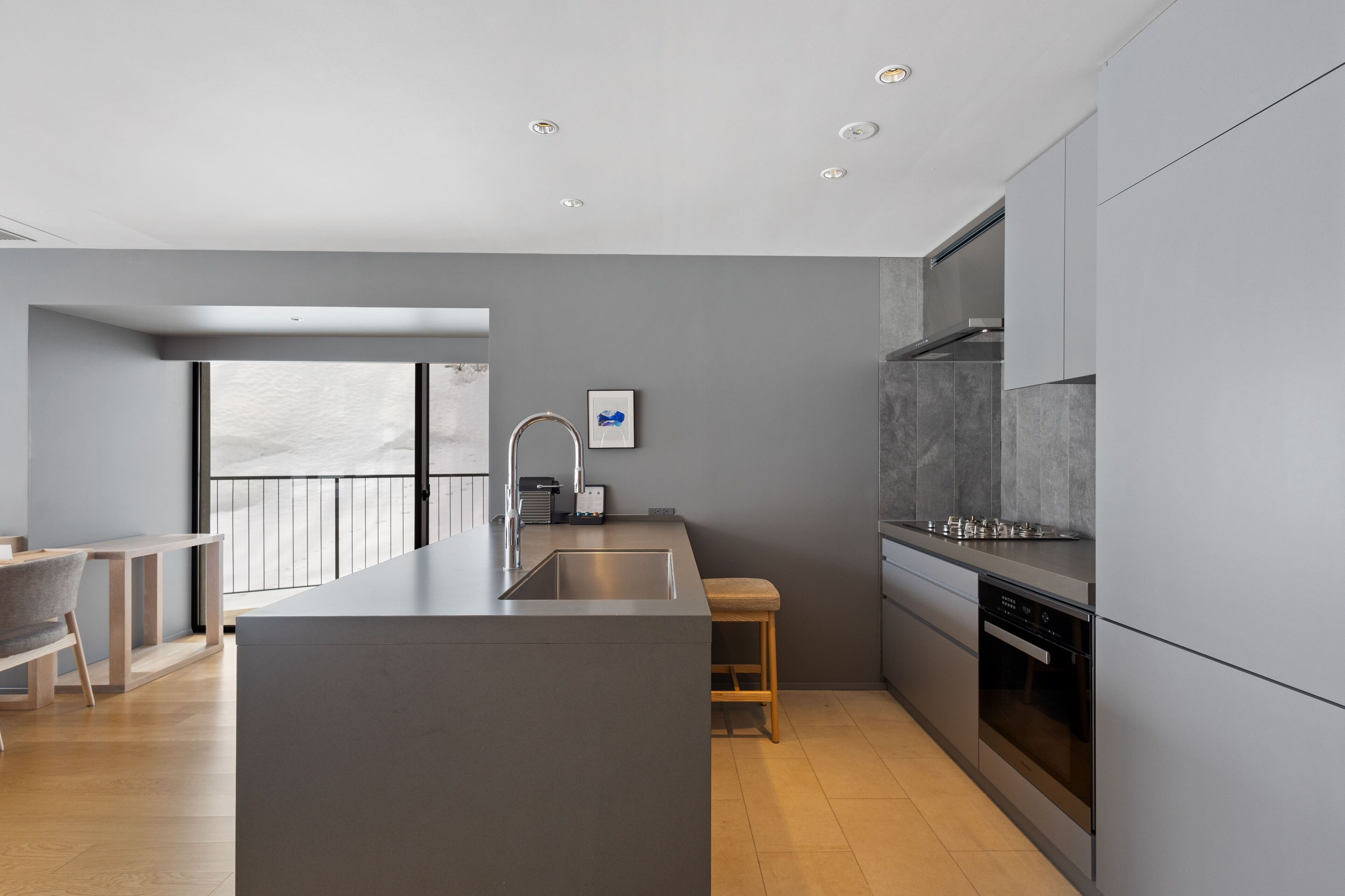 A modern kitchen with a central island, built-in appliances, and a view to the outside.