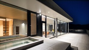 A modern building with a glass facade, a pool, and a seating area.
