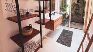 Un baño moderno con un estante empotrado, un espejo y vistas al exterior a través de una puerta de vidrio.