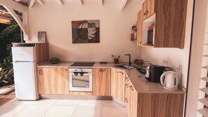 Una cocina moderna con armarios de madera, un refrigerador blanco, una estufa y un lavamanos. Hay un cuadro en la pared y una ventana que proporciona luz natural.