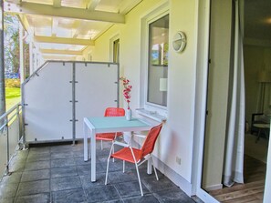 A covered patio area with a table and chairs, a window with a view, and a door leading to another room. - Close to the beach, balcony, free AHOI adventure pool - Strandresidenz Brandenburg FeWo 07 (Göhren)