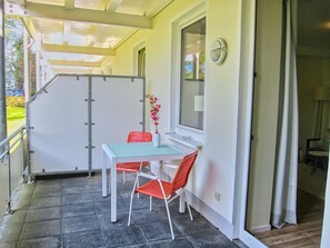 A covered patio area with a table and chairs, a window with a view, and a door leading to another room. - Close to the beach, balcony, free AHOI adventure pool - Strandresidenz Brandenburg FeWo 07 (Göhren)