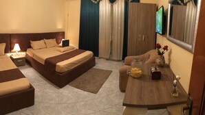 Habitación de hotel con dos camas, un escritorio con lámpara, televisión y un florero con flores.