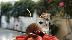 Un plato de sandía, kiwi y uvas, junto a un vaso de agua y un coco sobre una mesa.