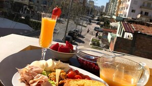 Una mesa de desayuno con un plato de comida, un vaso de zumo de naranja y un bol de fresas.