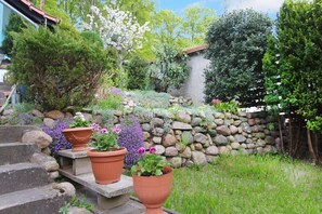 A garden with a stone wall, potted plants, and a staircase leading up to a house.