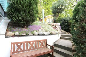 A wooden bench in a garden area with a stone wall and plants.
