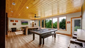A spacious room with a pool table, wooden flooring, and large windows offering a view of greenery. - Firefly Haus - Hot Tub, Firepit, 10min to Smokies (Gatlinburg)