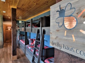 A bunk bed room with a wooden ceiling and a sign reading "firefly-haus.com".