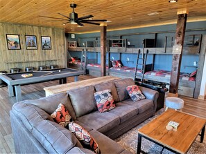 Relax in the lounge area with a pool table, comfortable sofa, and wooden coffee table.