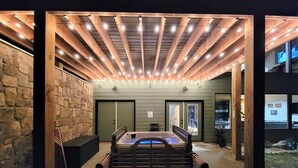An outdoor seating area with a wooden bench and a hot tub. - Firefly Haus - Hot Tub, Firepit, 10min to Smokies (Gatlinburg)
