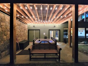 Relax in a serene outdoor space with a hot tub and comfortable seating area under a pergola.