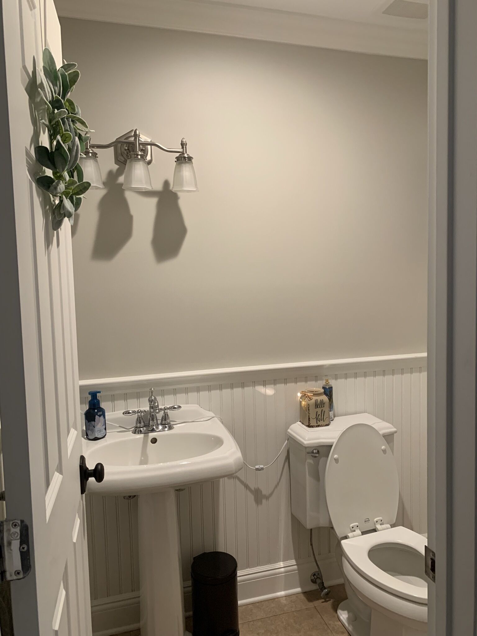 A bathroom with a white sink, toilet, and a wall-mounted light fixture.