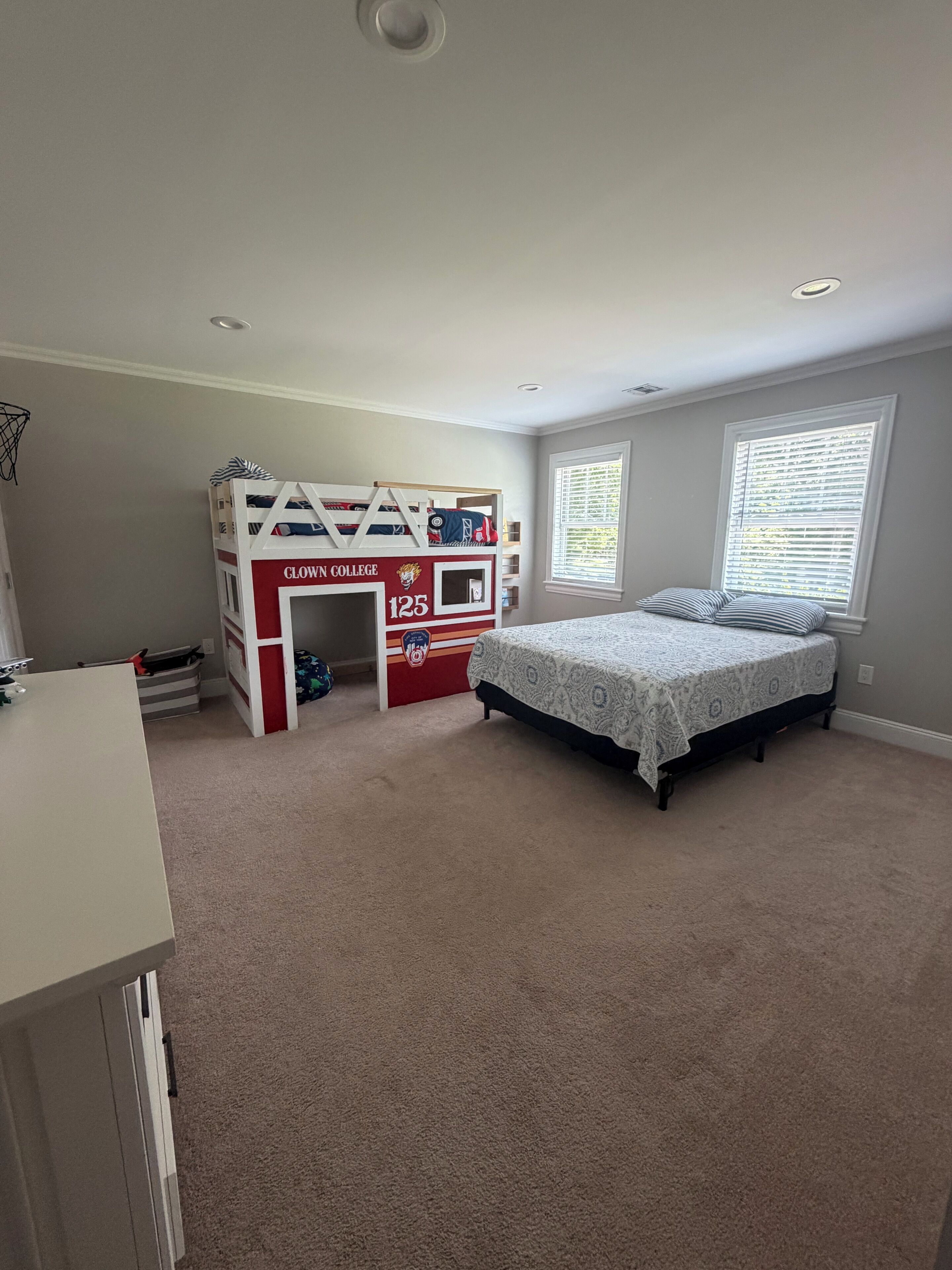 A bedroom with a bunk bed, a desk, and a bed.