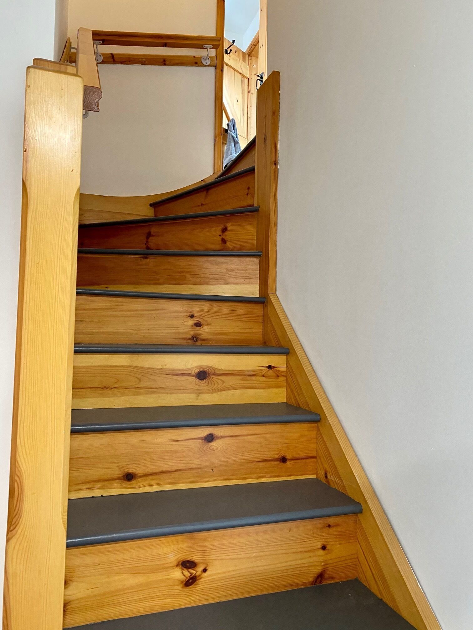 A wooden staircase with a handrail, leading to a landing.