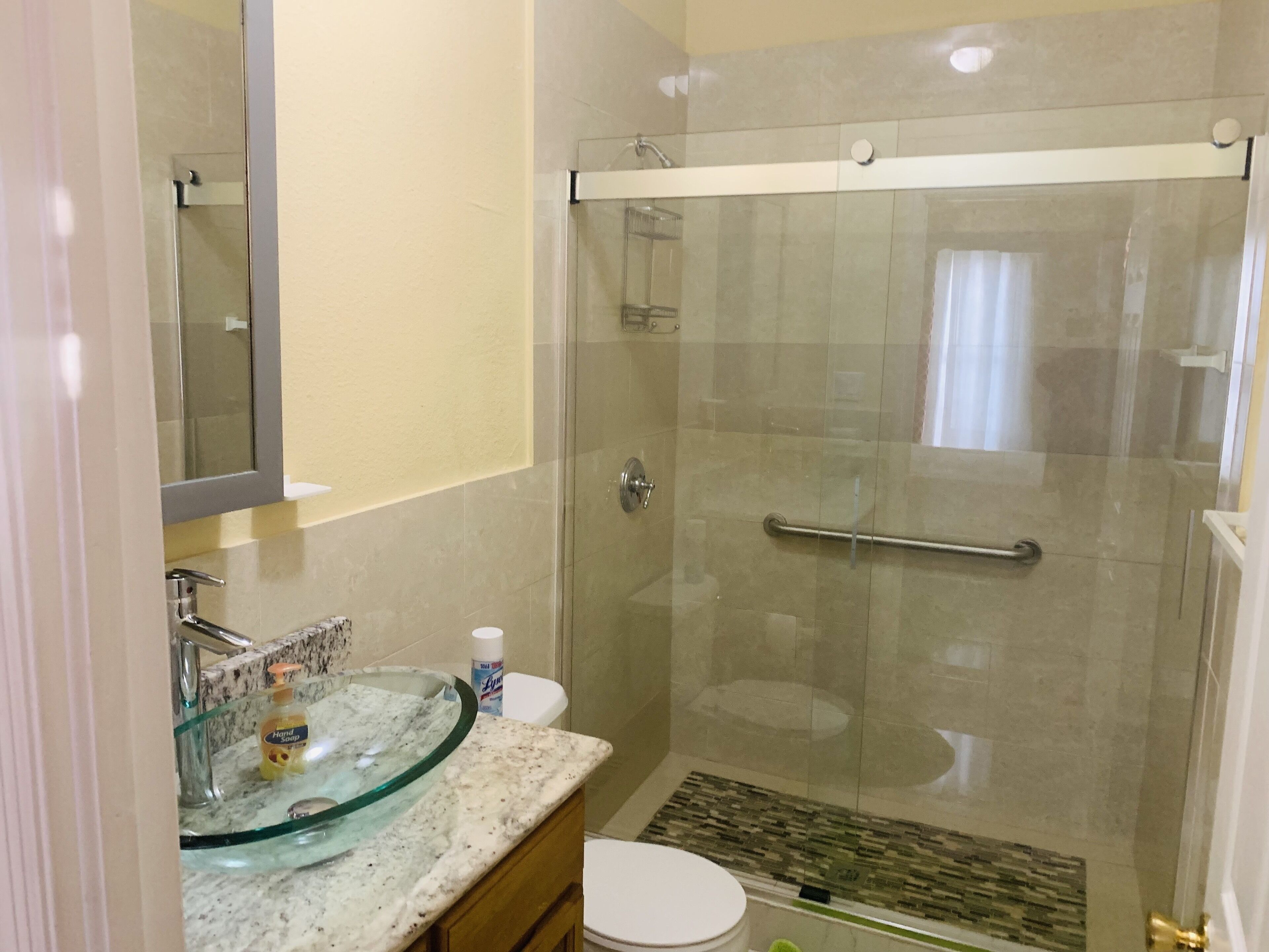A modern bathroom with a glass shower enclosure, a marble sink, and a toilet.